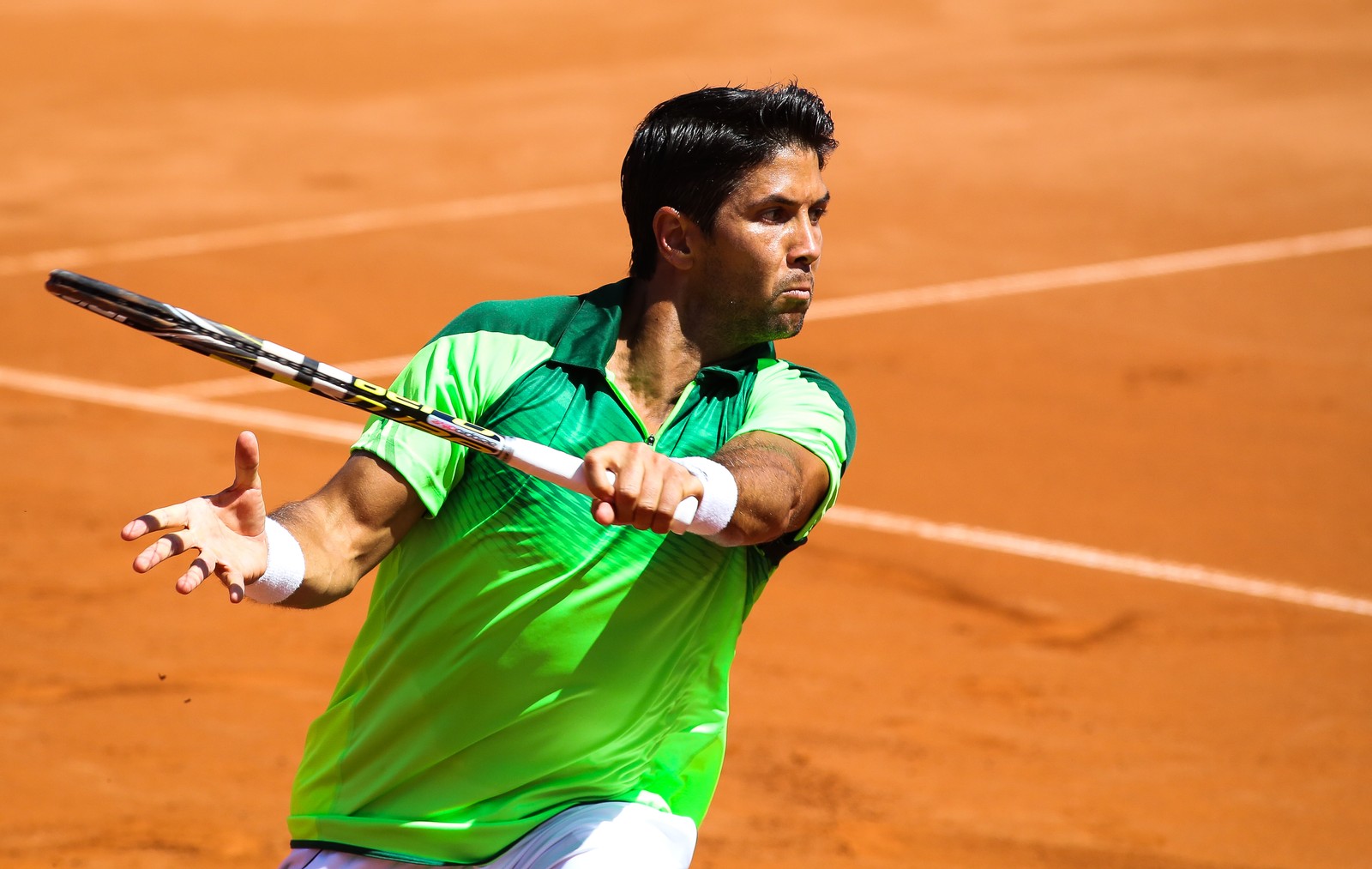 Um tenista de camisa verde e shorts brancos balançando uma raquete (tênis, tennis, tenista, esportes, local desportivo)