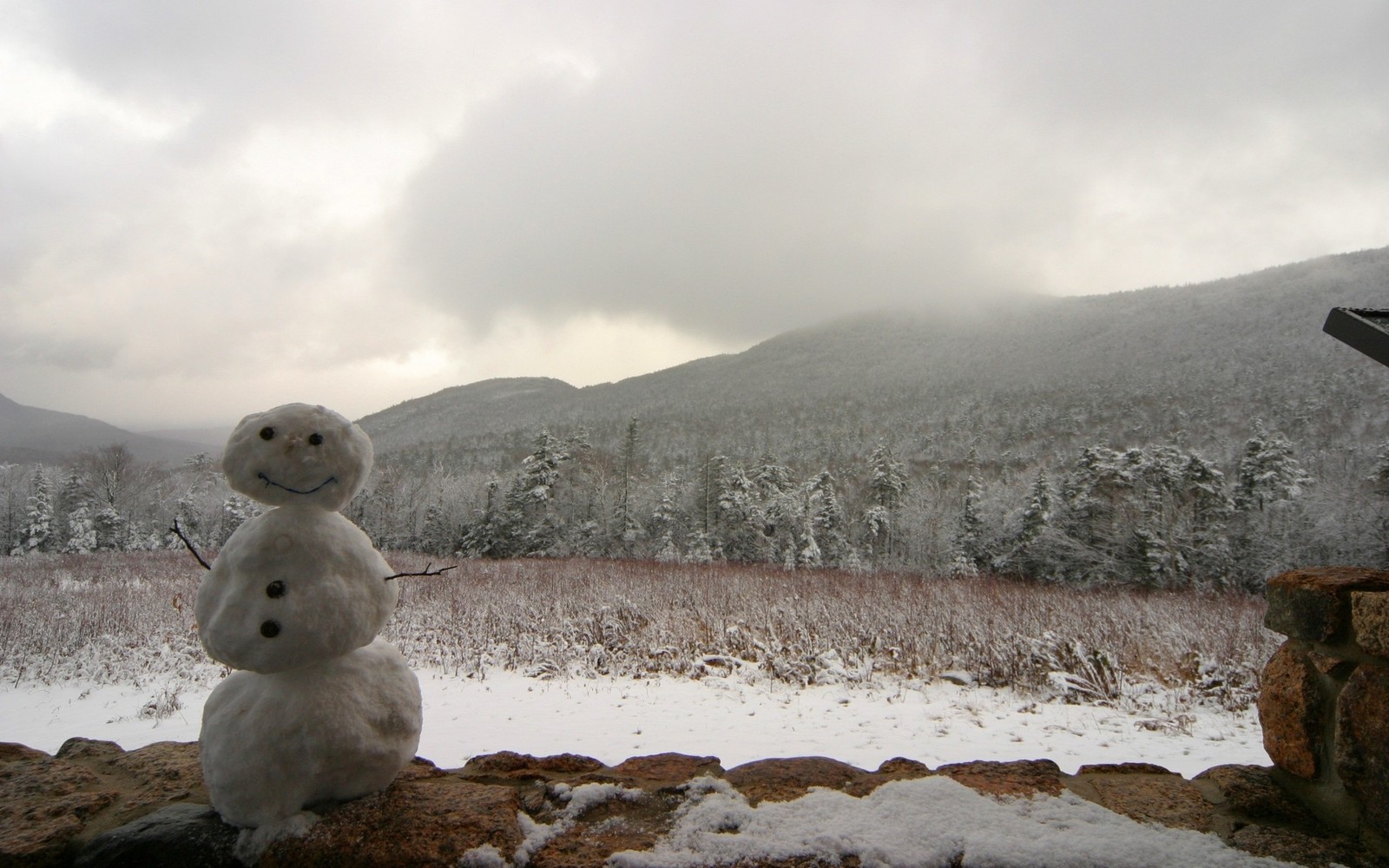 Es sitzt ein schneemann auf einem stein (schneemann, schnee, gefrieren, berge, wolken)