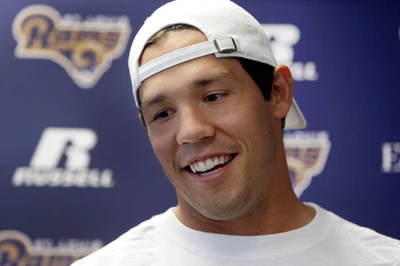 Jogador sorridente de boné durante a coletiva de imprensa da NFL, representando o Philadelphia Eagles.