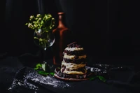 Decadent chocolate torte layered with creamy filling, elegantly presented on a dark backdrop.