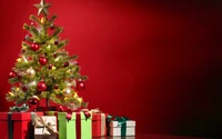 Festively decorated Christmas tree with ornaments and presents against a red background.