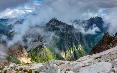 Majestätische Bergkette umgeben von Wolken und üppiger Wildnis