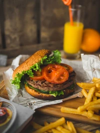 Hambúrguer suculento com alface fresca e tomate, servido ao lado de batatas fritas douradas e uma bebida refrescante.