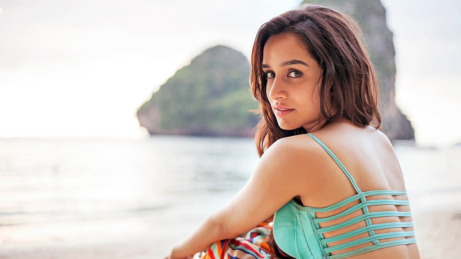 Una mujer sentada en la playa con una toalla colorida (shraddha kapoor, celebridad, actriz, bollywood, chicas)