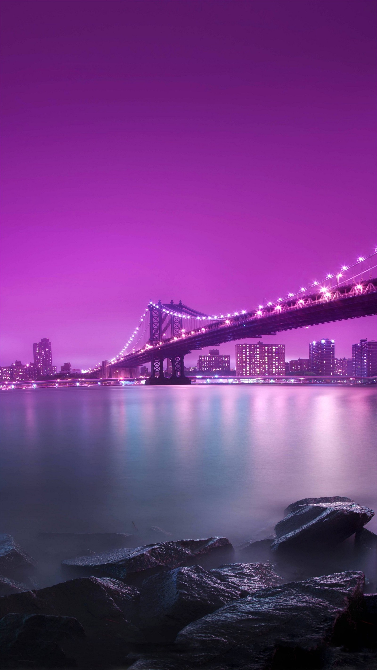 Cielo púrpura sobre la ciudad y el agua con rocas en primer plano (hermoso, puente, ciudad, galaxia, paisaje)