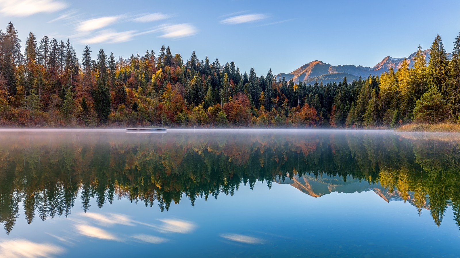 Uma vista de um barco em um lago cercado por árvores (crestasee lake, árvores de outono, suíça, reflexo, lago espelho)