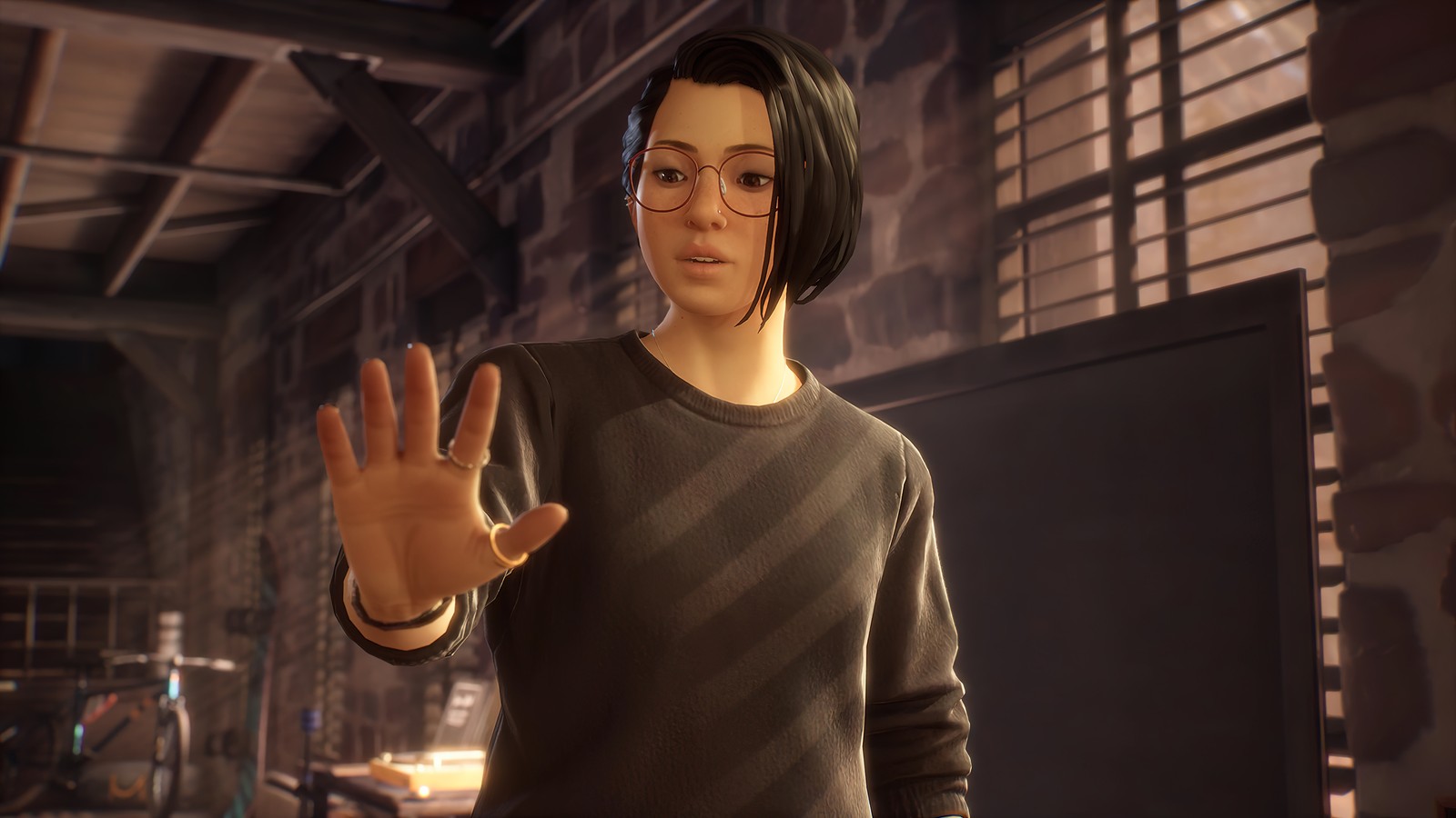 Una mujer con una camisa negra y gafas levantando las manos (life is strange true colors, videojuego, alex chen)