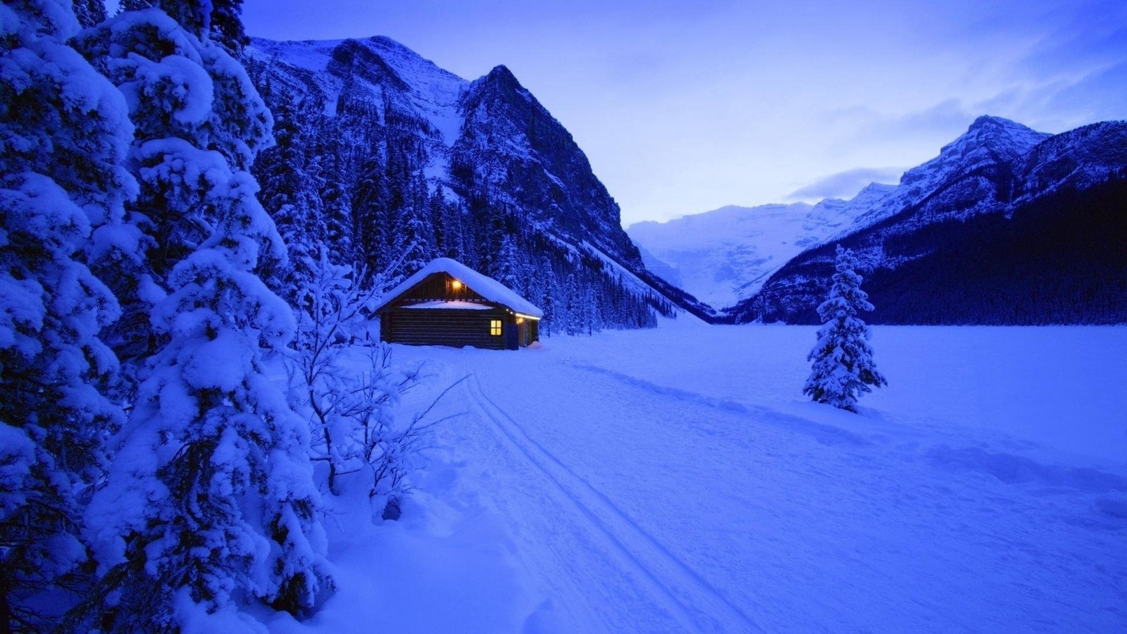 Une cabane enneigée dans les montagnes avec une lumière allumée (lac louise, lake louise, lac moraine, lac, montagne)