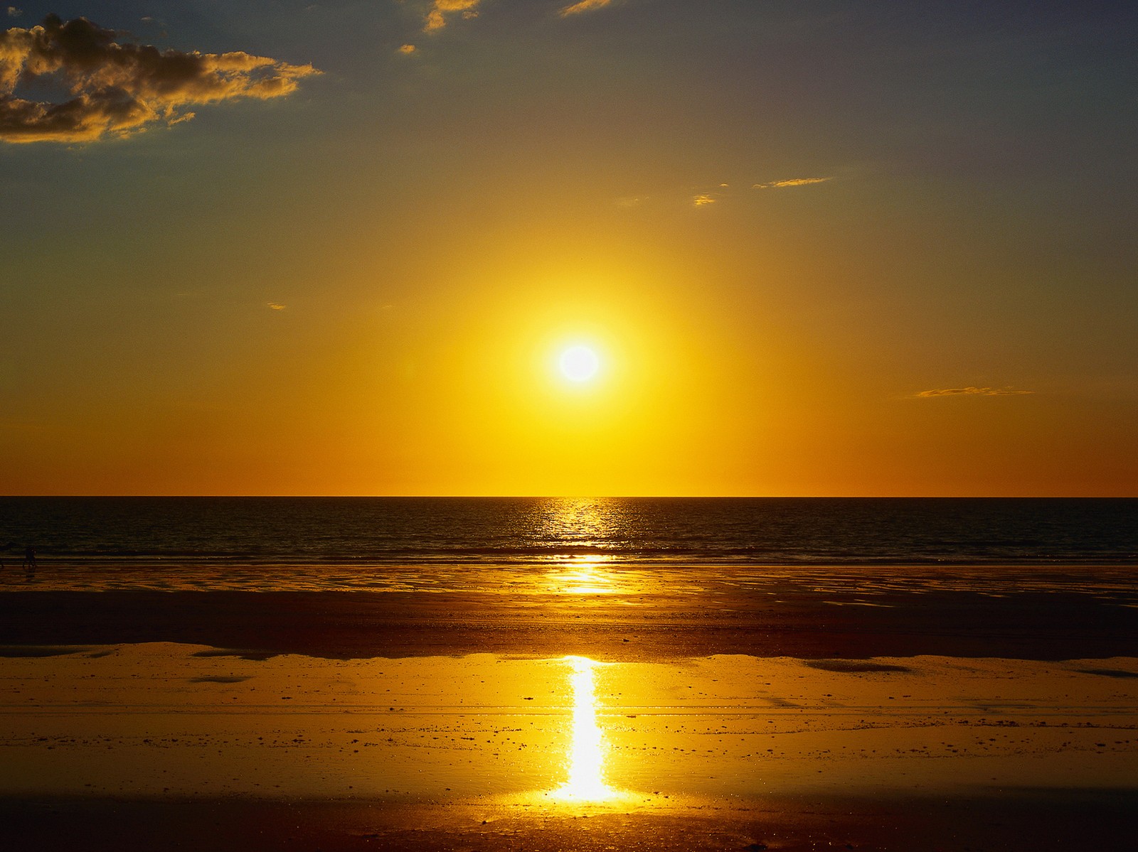 A view of a beach with a person walking on the sand at sunset (rise, sea, sun)