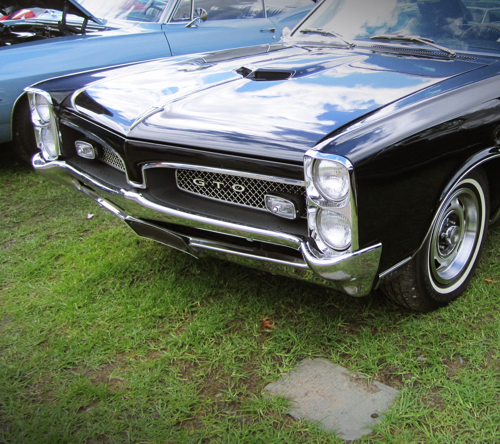 Il y a une voiture noire garée dans l'herbe avec d'autres voitures (auto, classique, gto, muscle car, pontiac)