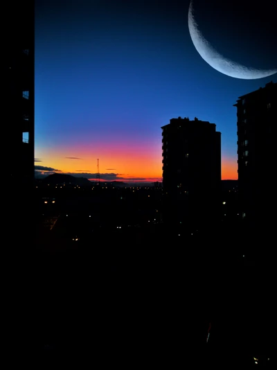 Paisaje urbano al atardecer bajo una luna creciente