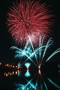 Exibição vibrante de fogos de artifício celebrando a véspera de Ano Novo sobre um reflexo sereno