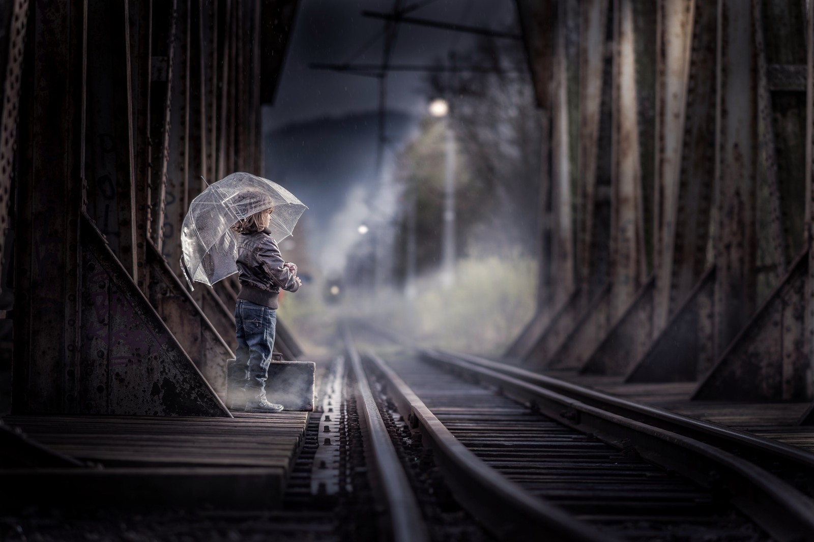 Hay una niña pequeña que sostiene un paraguas en las vías del tren (chica linda, vías del tren, estación de tren, paraguas, día lluvioso)