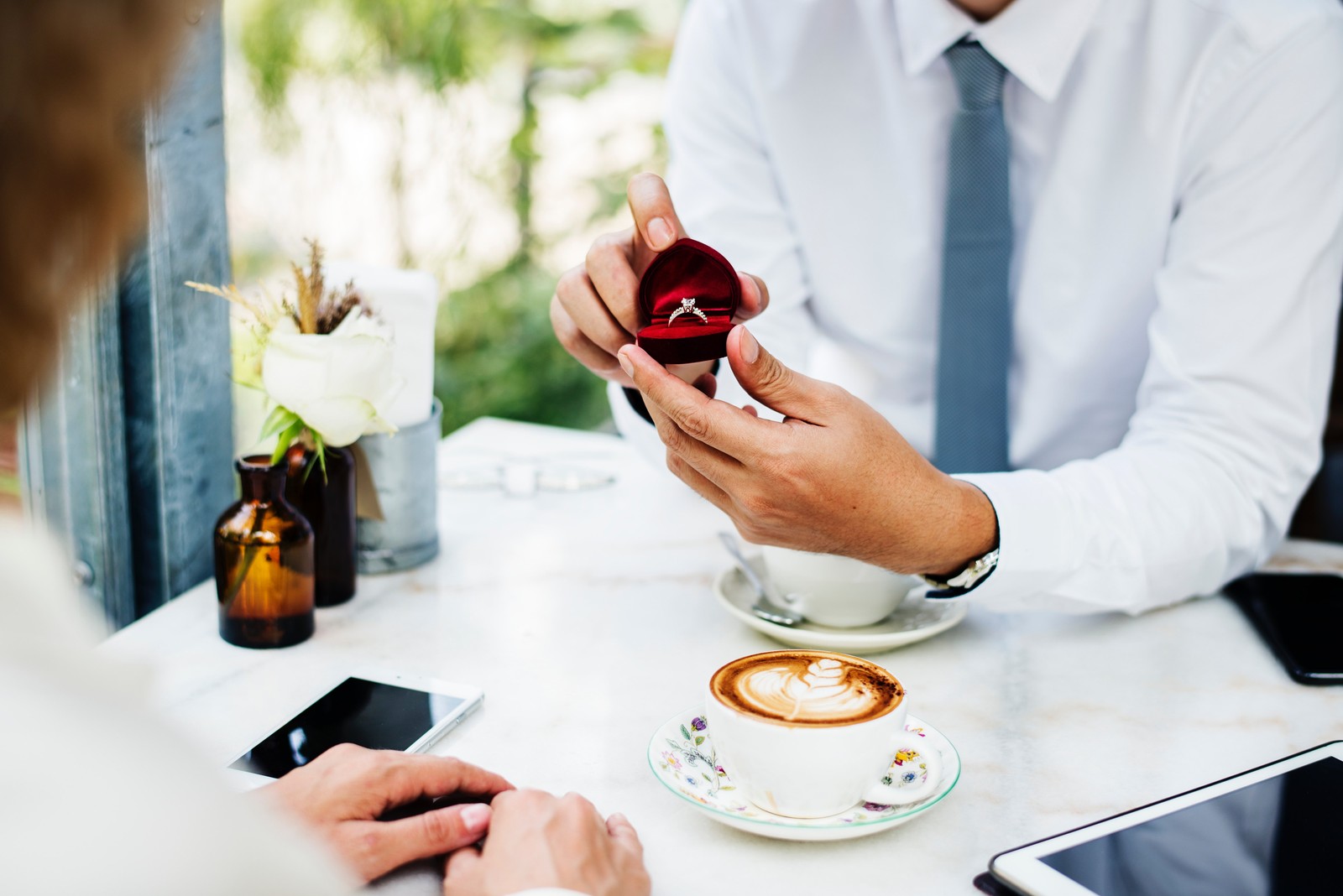 Quelqu'un tient une bague et une tasse de café sur une table (mariage, table, partenaire significatif, amour, petit ami)