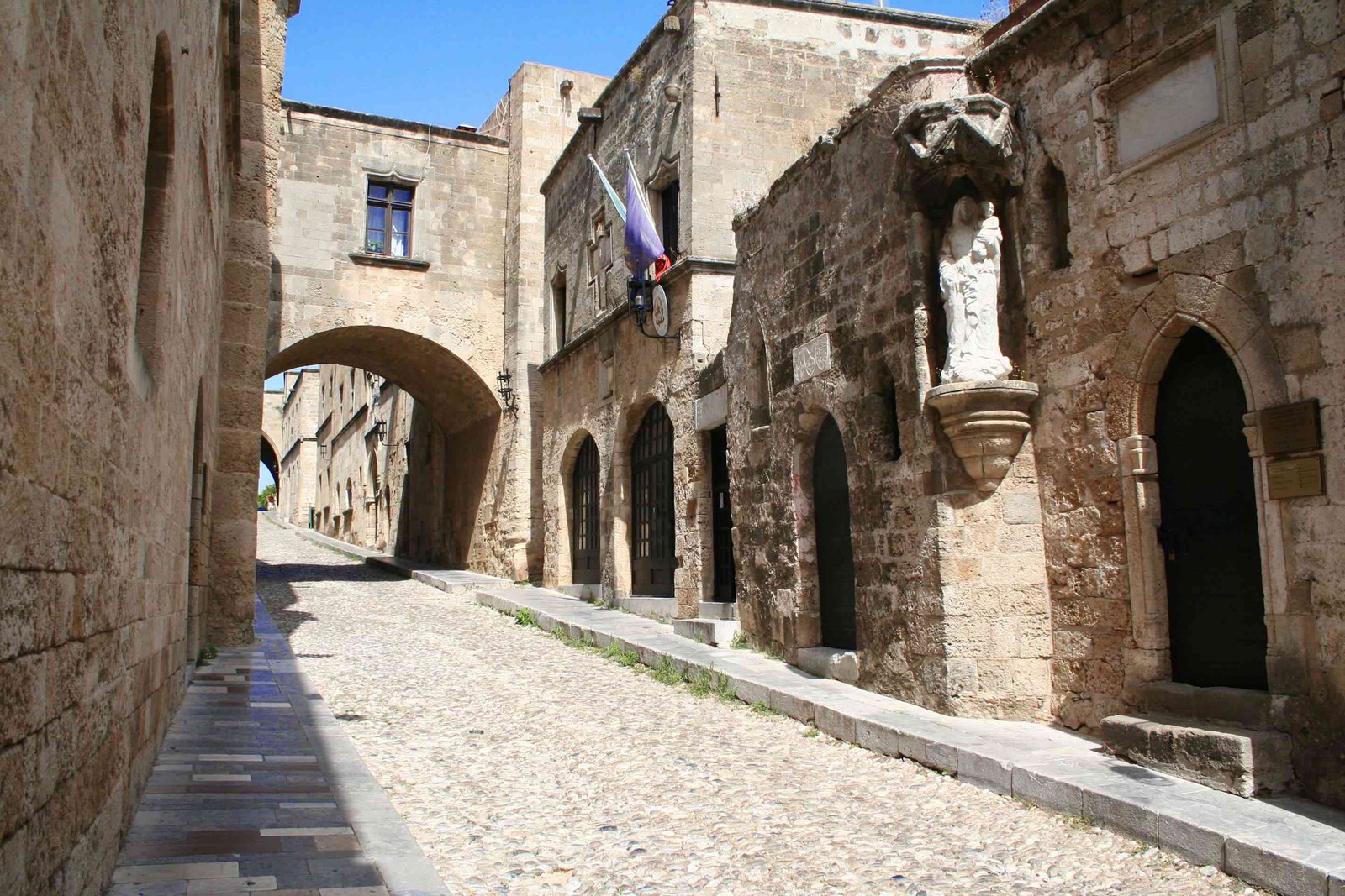 Vista aérea de un callejón de piedra con arcos que conducen a edificios (arco, pueblo, calle, arquitectura medieval, callejón)