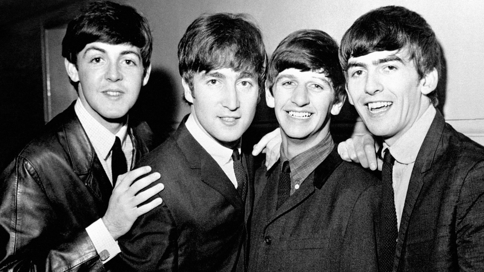 Arafed black and white photo of four men in suits posing for a picture (john lennon, ringo starr, paul mccartney, george harrison, the beatles)