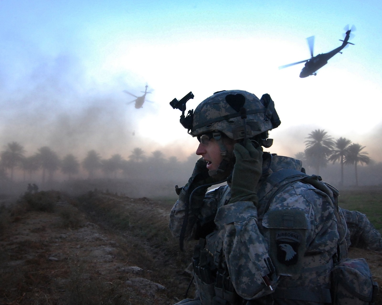 Arafed soldier in camouflage with a helicopter flying in the background (airborne, army)