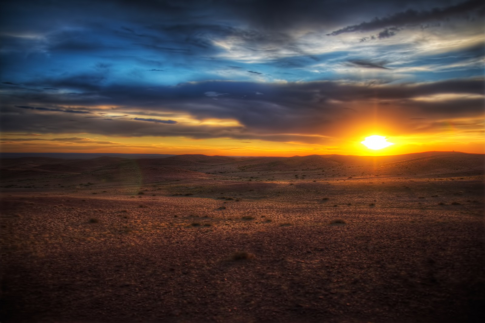 A view of a sunset over a desert plain with a few clouds (gobi desert, desert, sunset, horizon, sunrise)