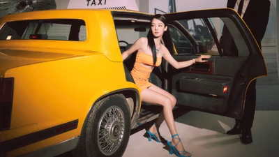 Hyoyeon from Girls' Generation exiting a classic yellow taxi, showcasing a stylish orange dress and vibrant blue heels.