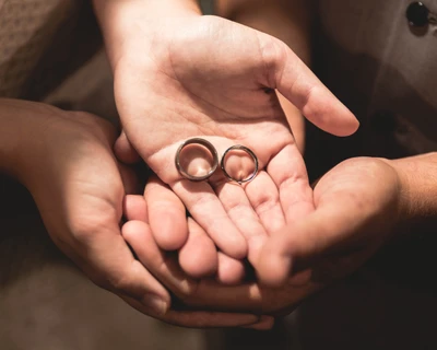 Manos entrelazadas sosteniendo anillos de boda