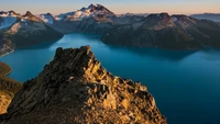 Majestic mountain range overlooking a serene crater lake at dawn.