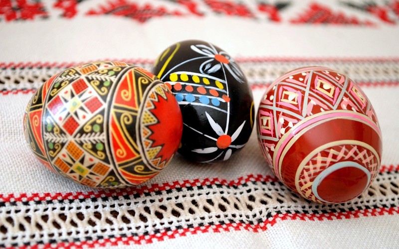 Три раскрашенных яйца лежат на скатерти (писанка, pysanka, пасхальное яйцо)