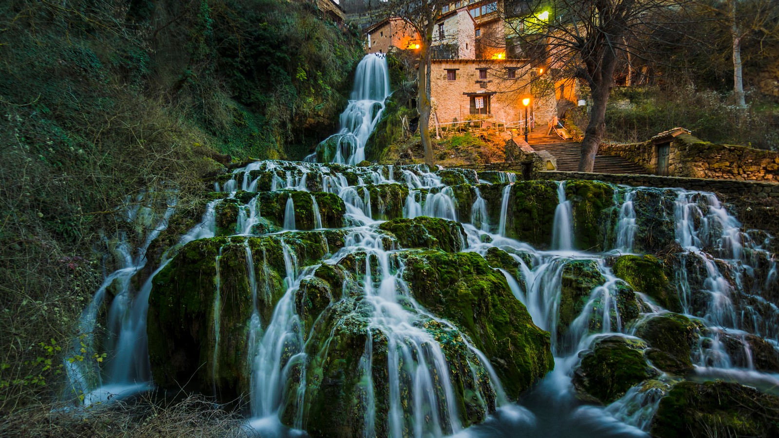 A waterfall in the middle of a forest with a house in the background (waterfall, water resources, body of water, nature, water)