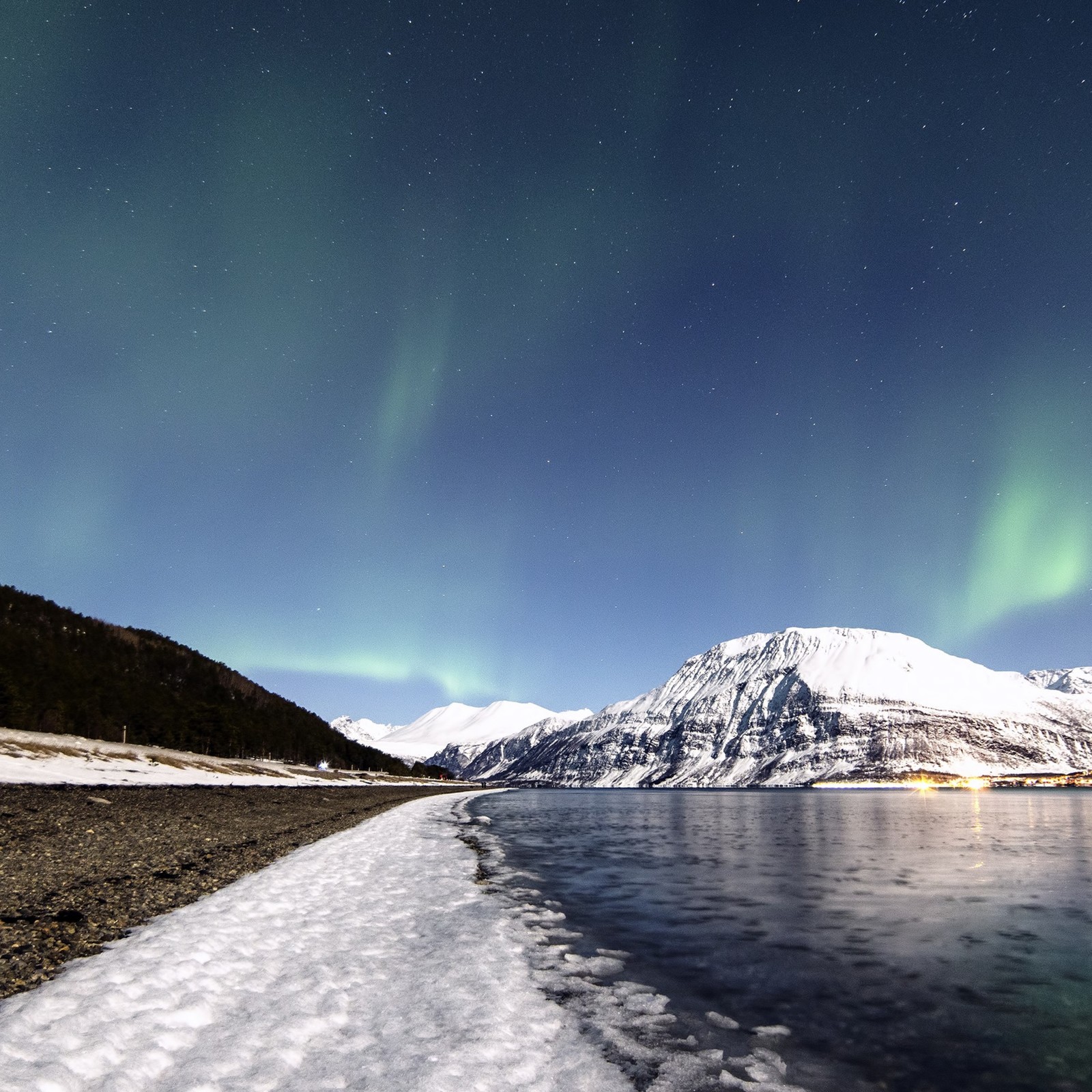 Vista arafed de um corpo de água com uma montanha ao fundo (aurora, natureza, neve, atmosfera, inverno)