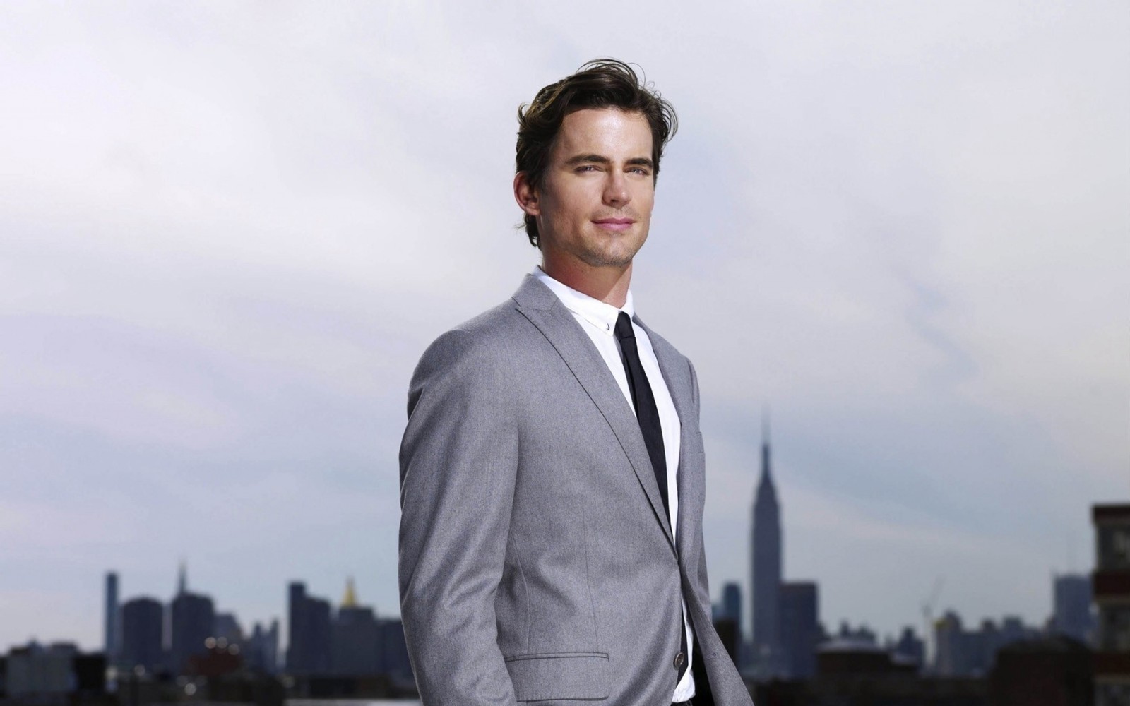 Arafed man in a suit and tie standing in front of a city skyline (television, suit, formal wear, outerwear, businessperson)