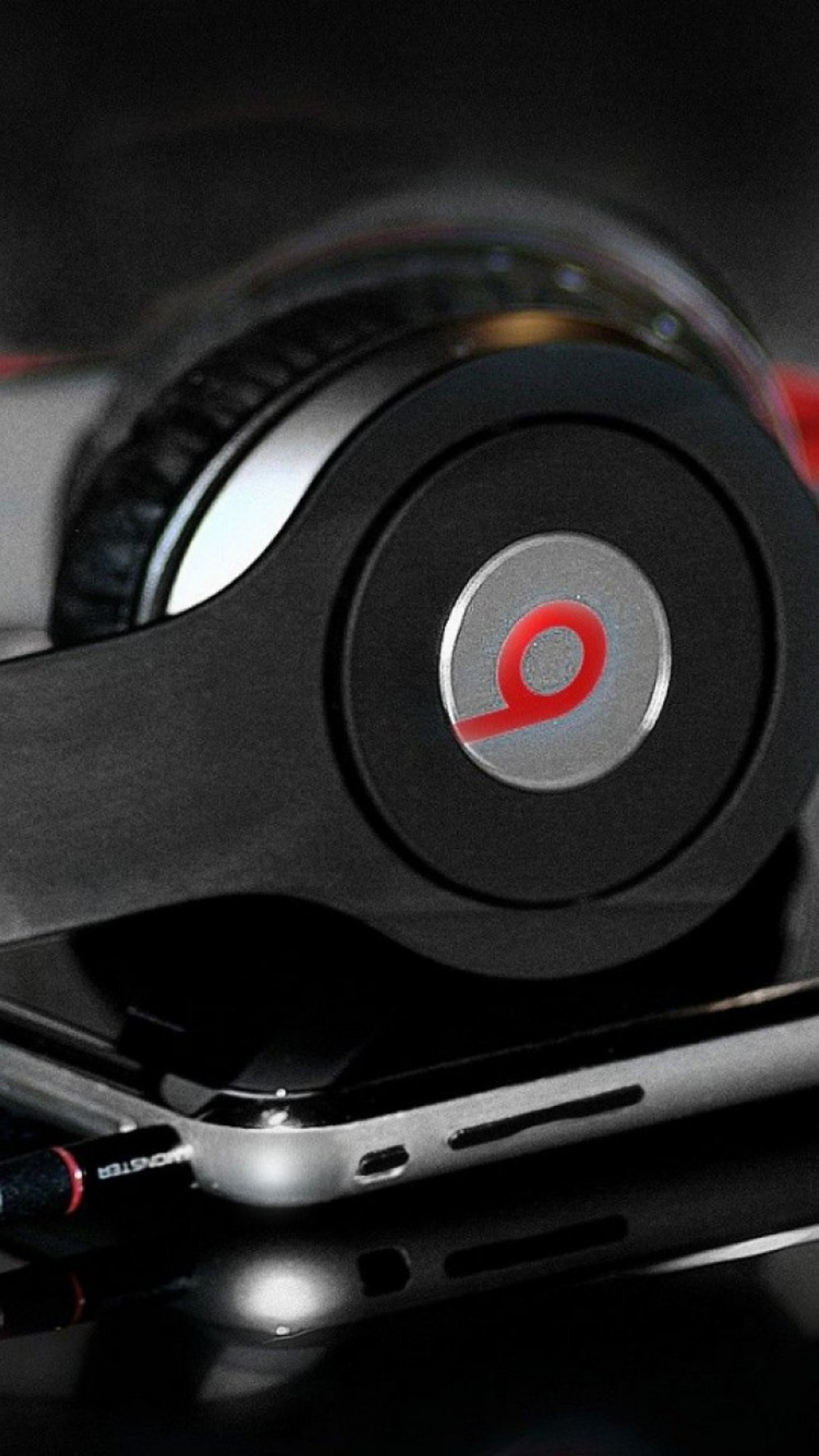 Há um fone preto com um botão vermelho nele (beats, ear headphone)