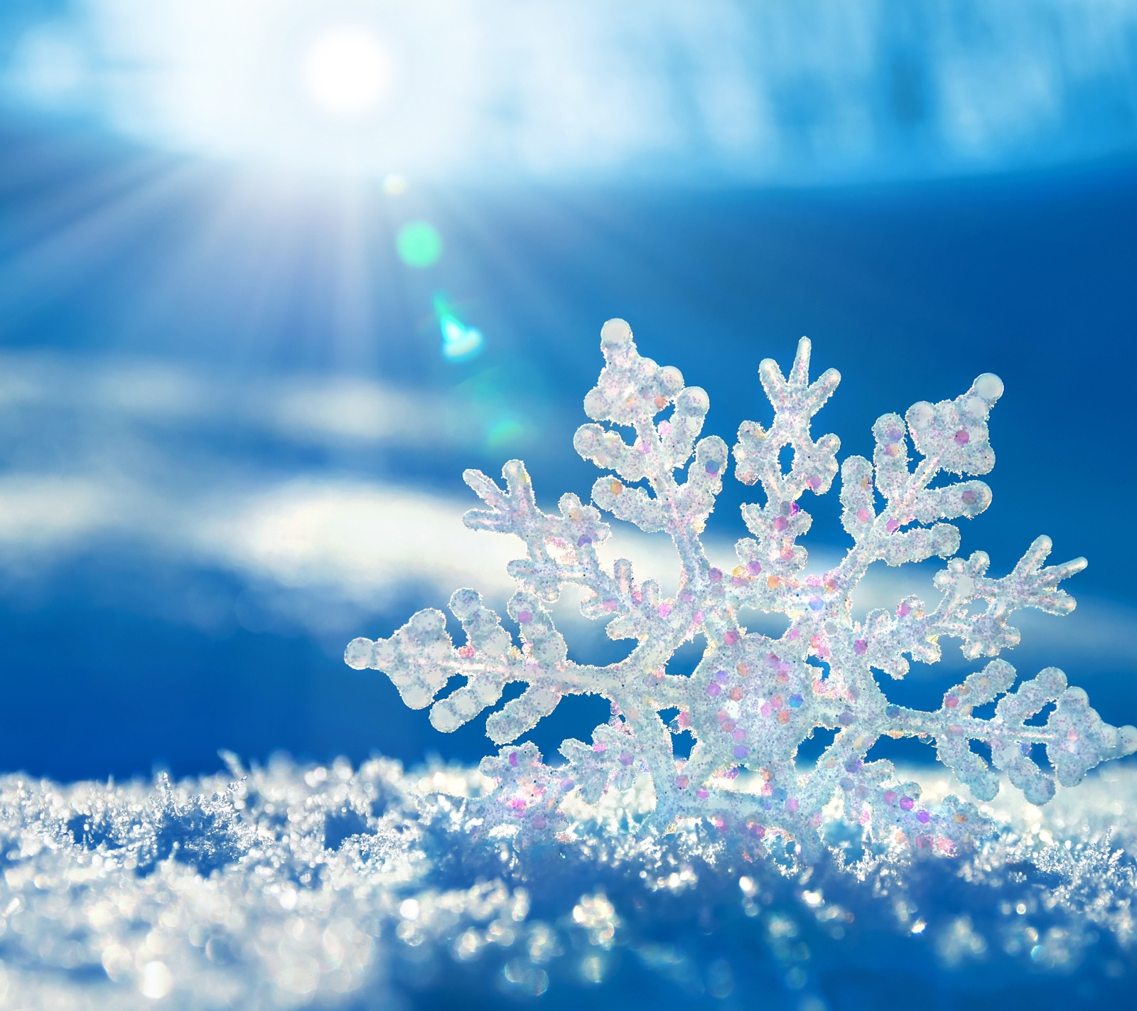 Snow flakes are on the snow with a bright sun in the background (blue, christmas, snowflake)