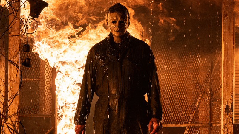 Мужчина в черной куртке стоит перед огнем (хэллоуин убивает, halloween kills, 2021, фильм, майкл майерс)