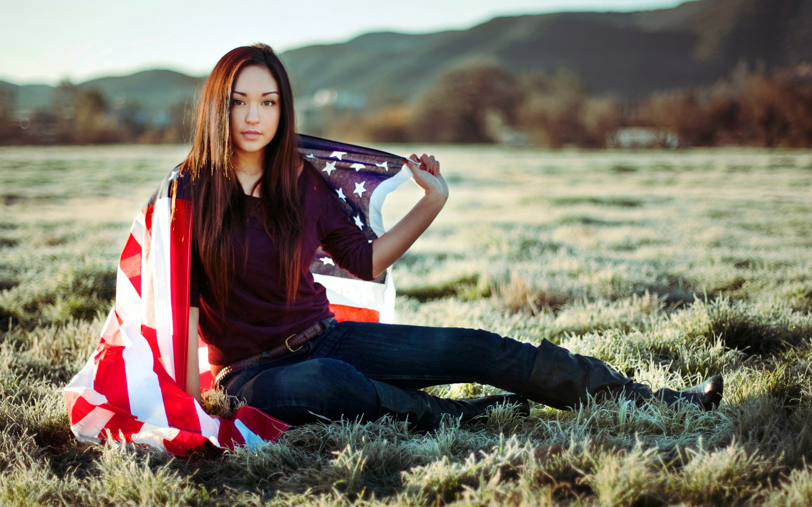 Arafed woman sitting in a field holding a flag (beauty, grass, sitting, long hair, woman)