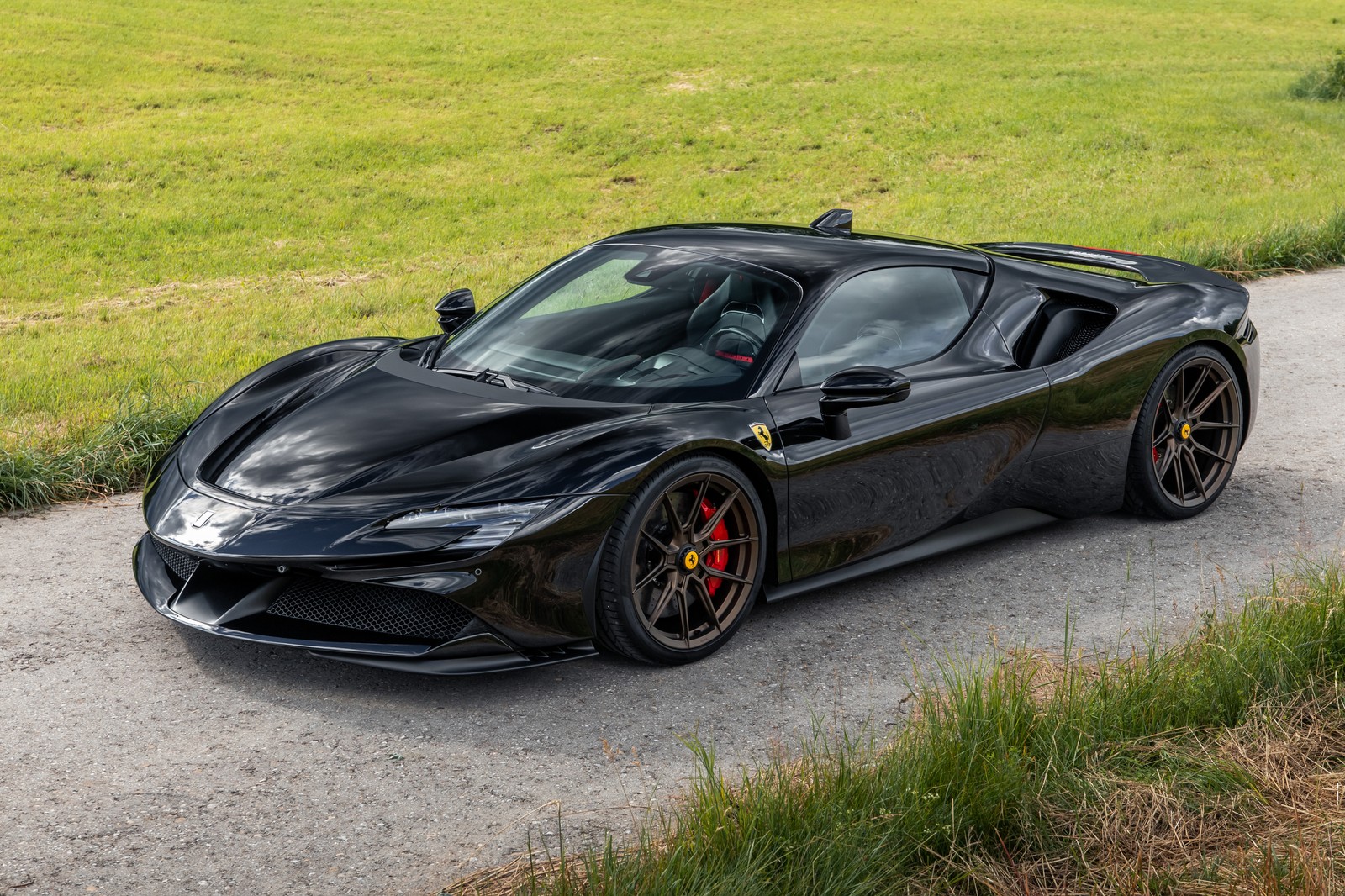 A black sports car driving down a road next to a field (novitec ferrari sf90 stradale, performance kit, 2021, 5k, black cars)