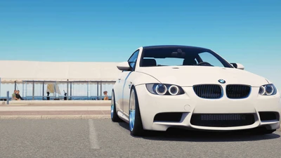 Élégante BMW M3 blanche garée au bord de la mer, mettant en valeur son design sportif et son attrait luxueux.