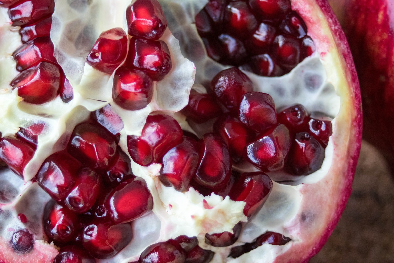 A close up of a pomegranate cut open on a table (pomegranate, fruit, berry, food, superfood)