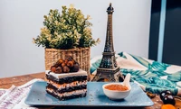 Capas decadentes de pastel de chocolate cubiertas con bayas, servidas con conservas de frutas y un toque de elegancia de una torre Eiffel en miniatura.