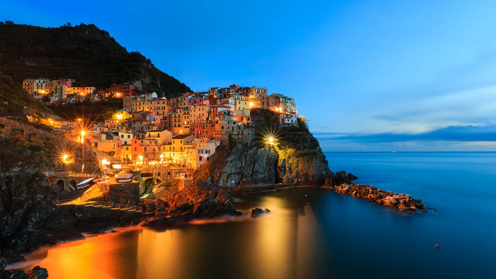 Uma vista de uma cidade na beira de um penhasco à noite (natureza, costa, mar, promontório, penhasco)