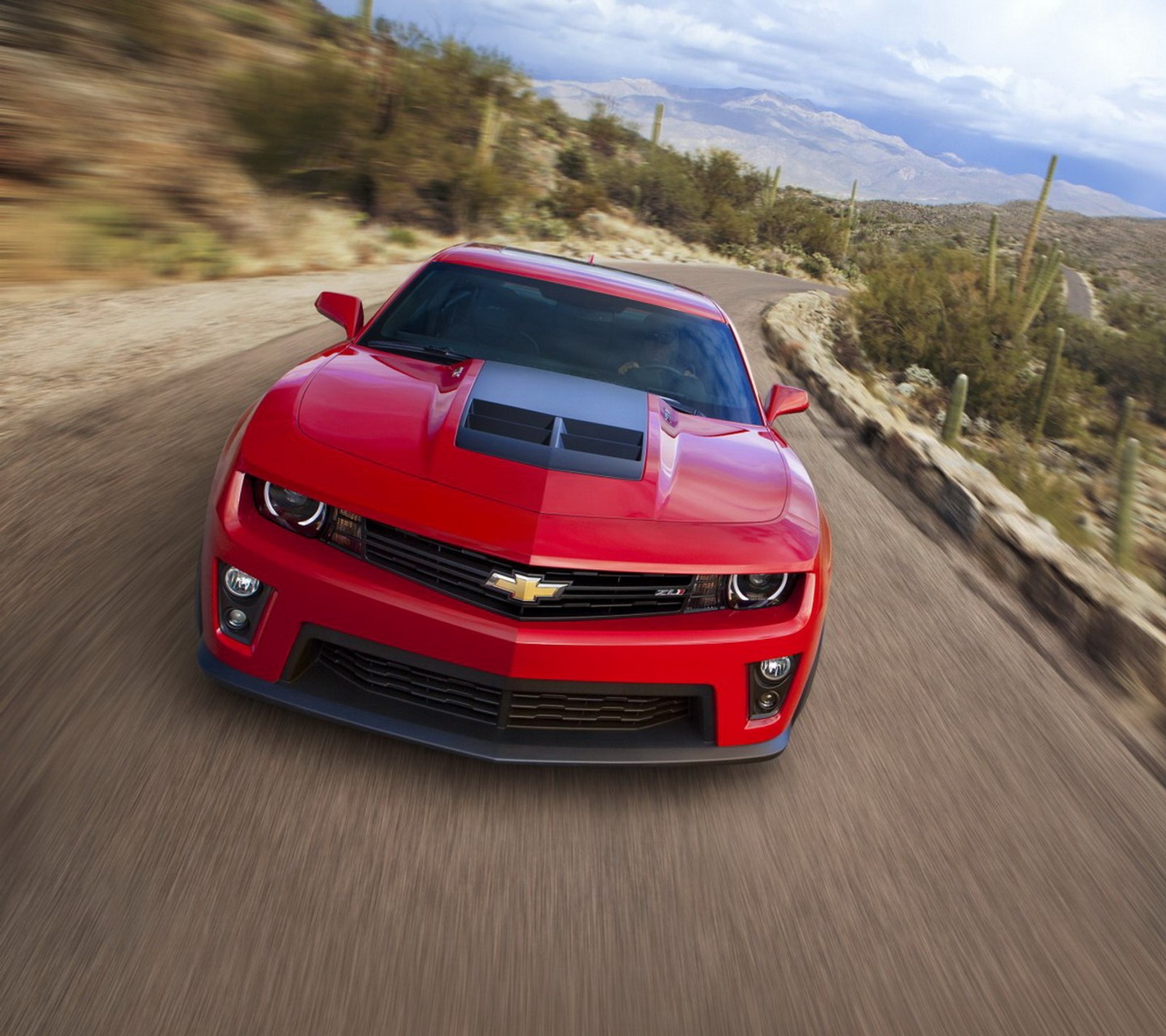 Une chevrolet camaro rouge roulant sur une route désertique (voiture, chevy camaro)