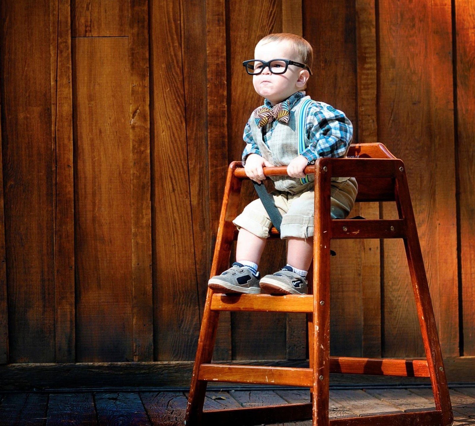 There is a small boy sitting in a high chair with a teddy bear (baby, funny)