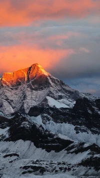 Pico dourado iluminado pelo nascer do sol entre nuvens dramáticas