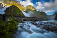 Majestätischer Wasserfall, der über eine Steinbrücke in einer üppigen Wildnis stürzt