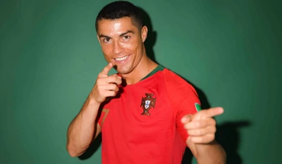 Cristiano Ronaldo con una camiseta roja de Portugal, señalando juguetonamente con un gesto de pulgar hacia arriba contra un fondo verde.