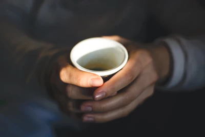 Warme Hände, die eine Kaffeetasse halten, genießen den Moment des Koffeinvergnügens.