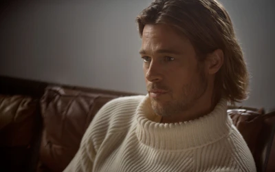 Brad Pitt in einem nachdenklichen Moment, trägt einen gemütlichen Pullover und zeigt seine markanten Gesichtszüge und seinen Bart.