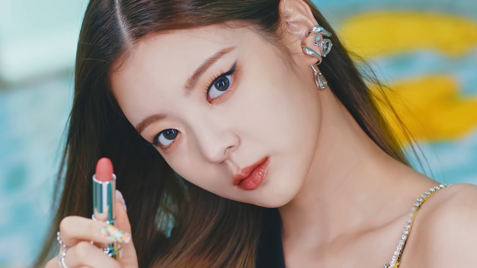 Une femme tenant un rouge à lèvres dans sa main et portant un collier (itzy, kpop, 있지, k pop, groupe de filles coréen)