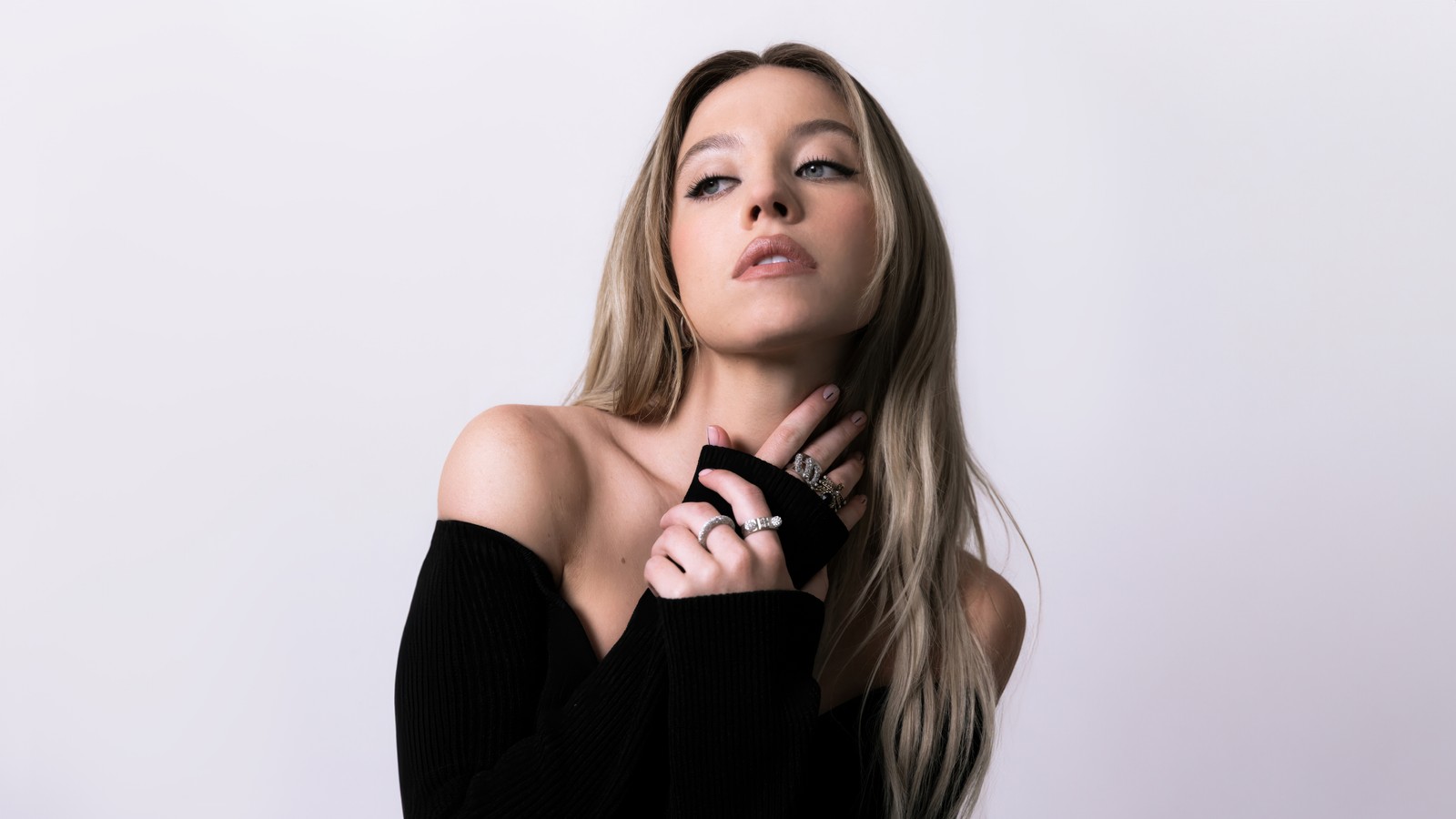 Femme blonde en haut noir et bracelets posant pour une photo (sydney sweeney, 2024, actrice américaine, fond blanc, 5k)