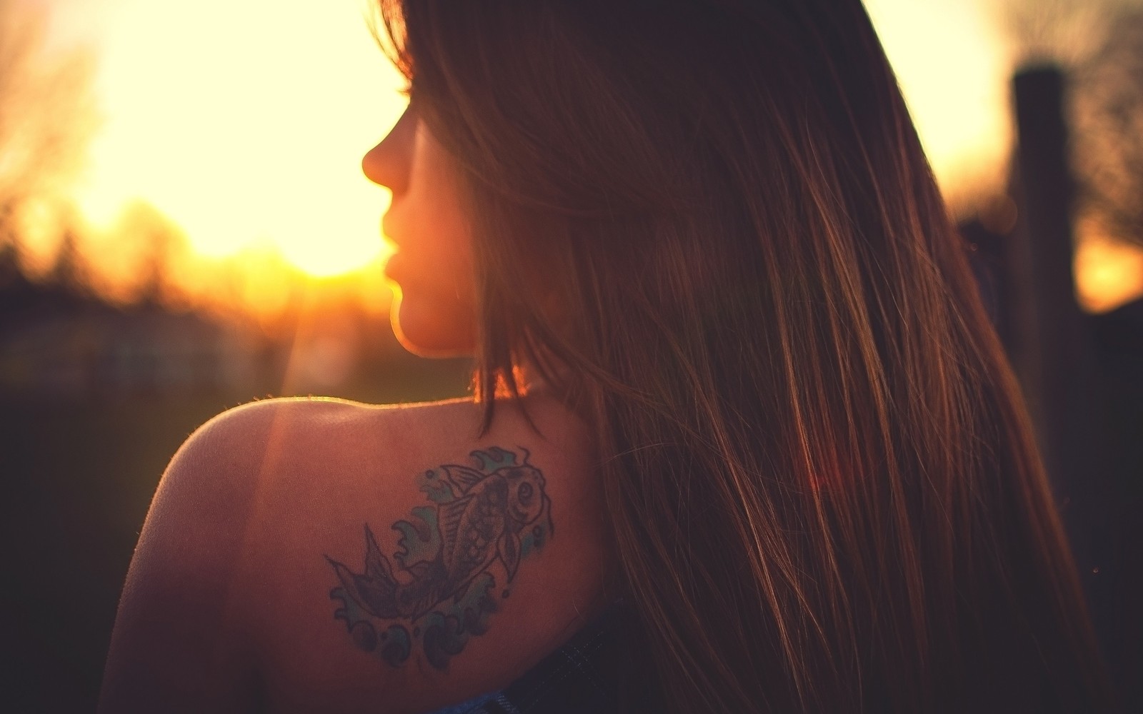 A close up of a woman with a tattoo on her back (blond, hair, shoulder, sunlight, neck)