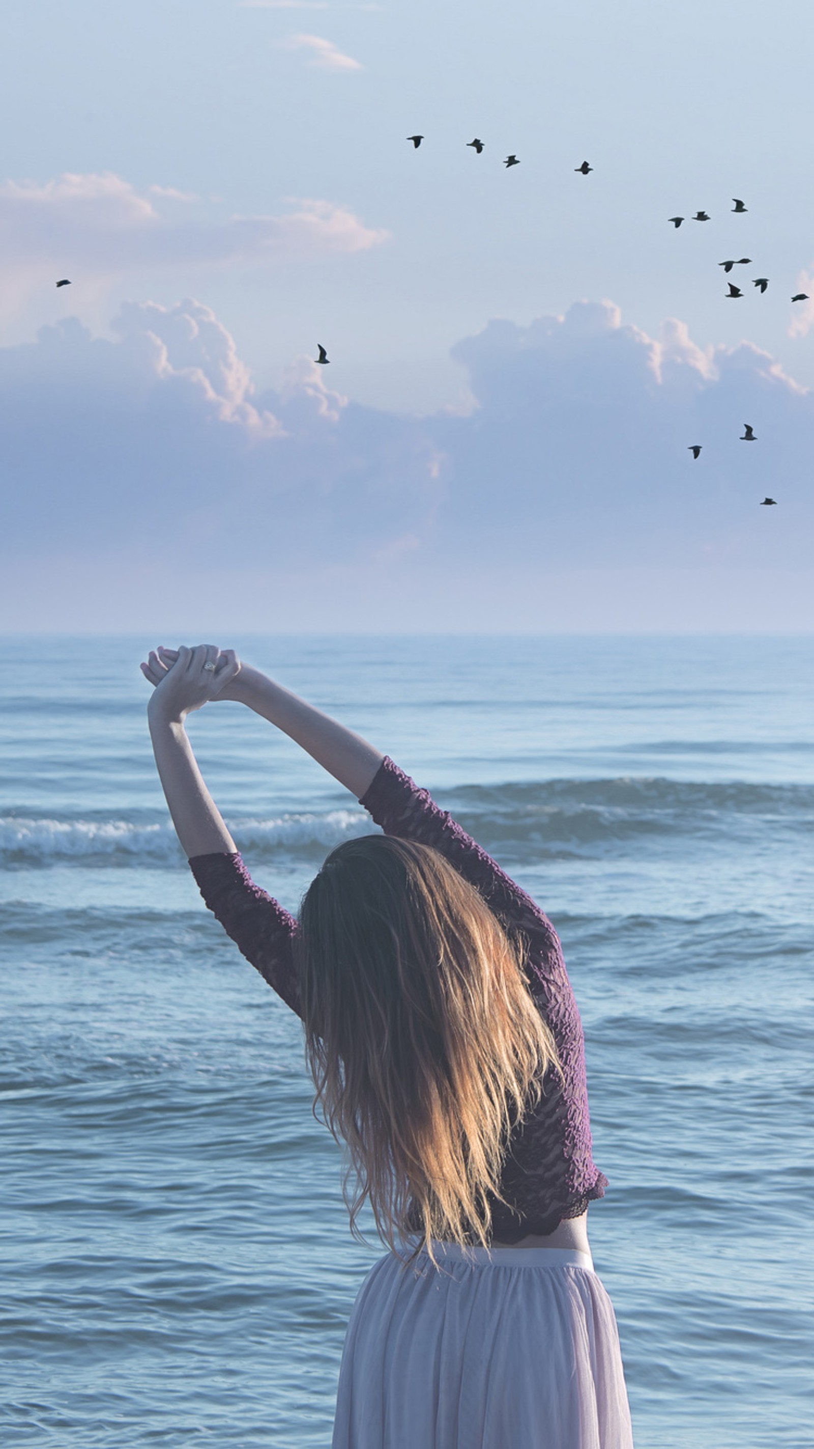 Eine frau steht am strand mit erhobenen armen (strand, vögel, mädchen, stimmung, leute)