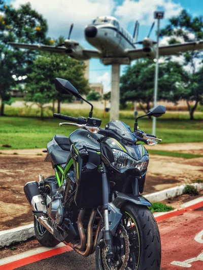 Motocicleta Kawasaki Z900 com avião clássico ao fundo